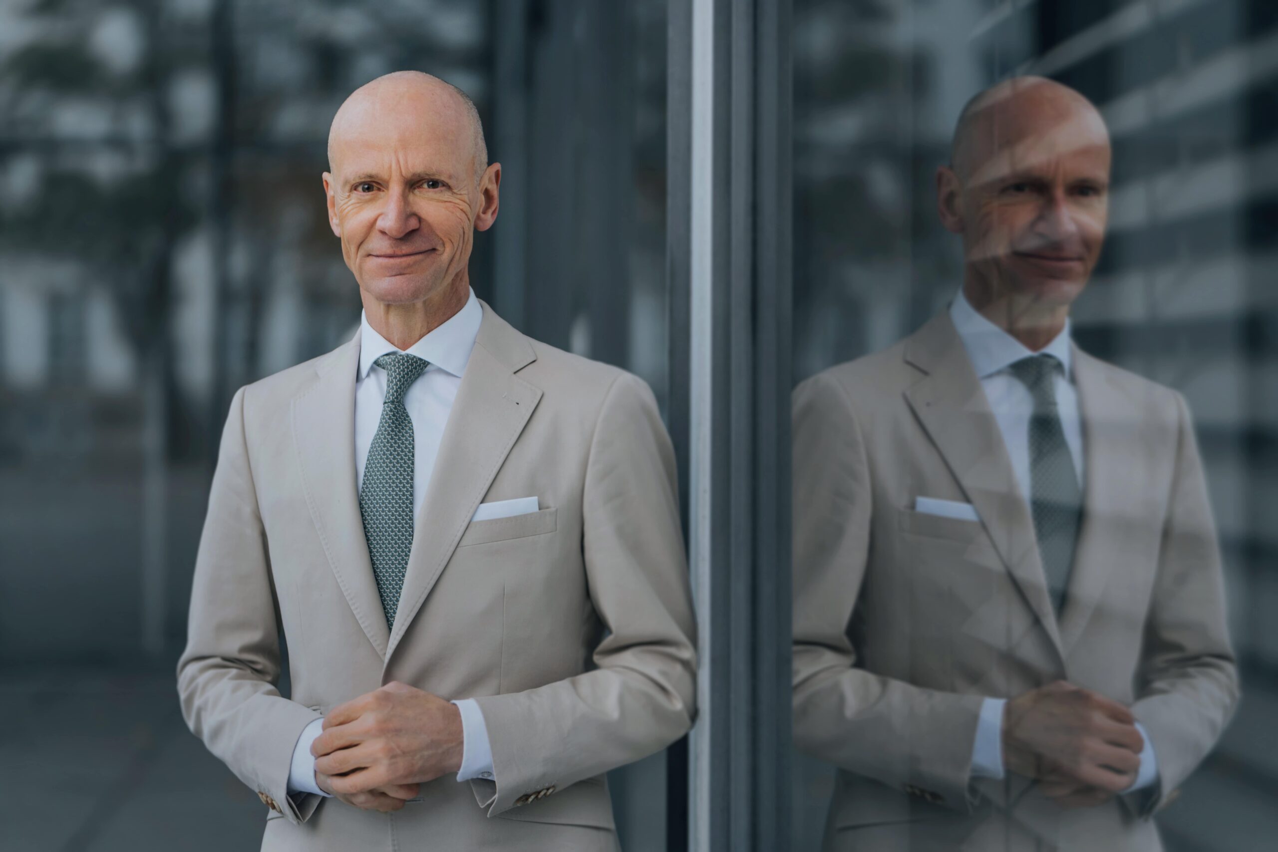 Portraitfoto von Dr. Gerd Kommer mit Spiegelung in einer Glasscheibe.