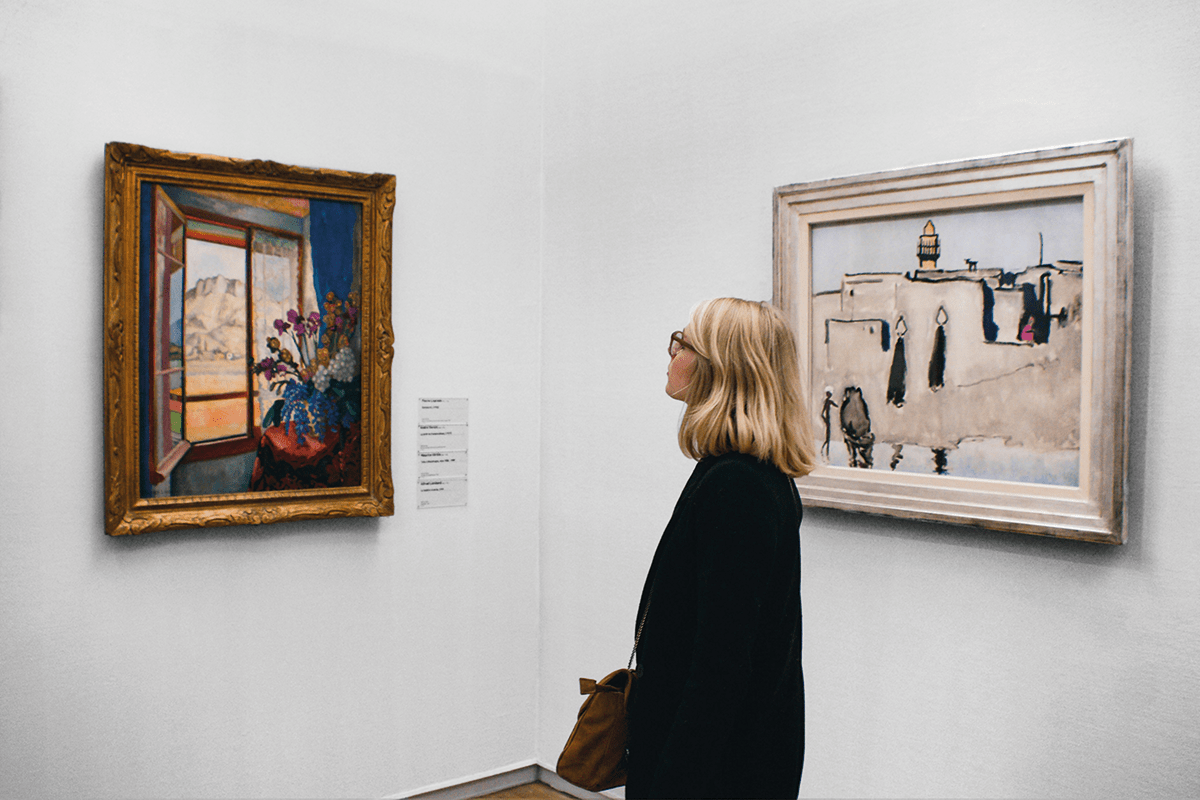 Frau betrachtet zwei Gemälde in einem Museum.